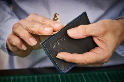 Porte-carte Magali Billy : idée cadeau en cuir artisanal, maroquinerie faite main, fabrication française. Ici ponçage du cuir avant teinture de tranche.
