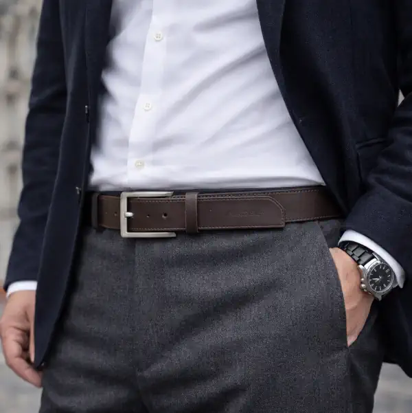 Ceinture en cuir marron, piqure marron et tranches teintées en marron. Boucle rectangulaire, argent satinée. Fabriquée dans notre atelier en Vendée. Portée gris.