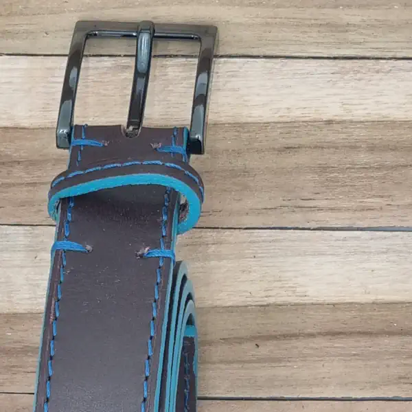 Ceinture en cuir marron avec une piqure bleu et les tranches teintées en bleu turquoise. Boucle de forme carrée, couleur canon de fusil. Boucle.
