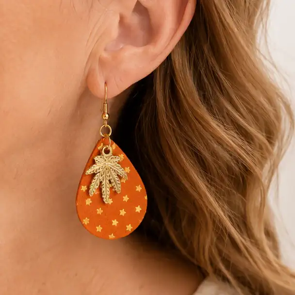 Boucles d'oreilles artisanales en cuir orange portées.