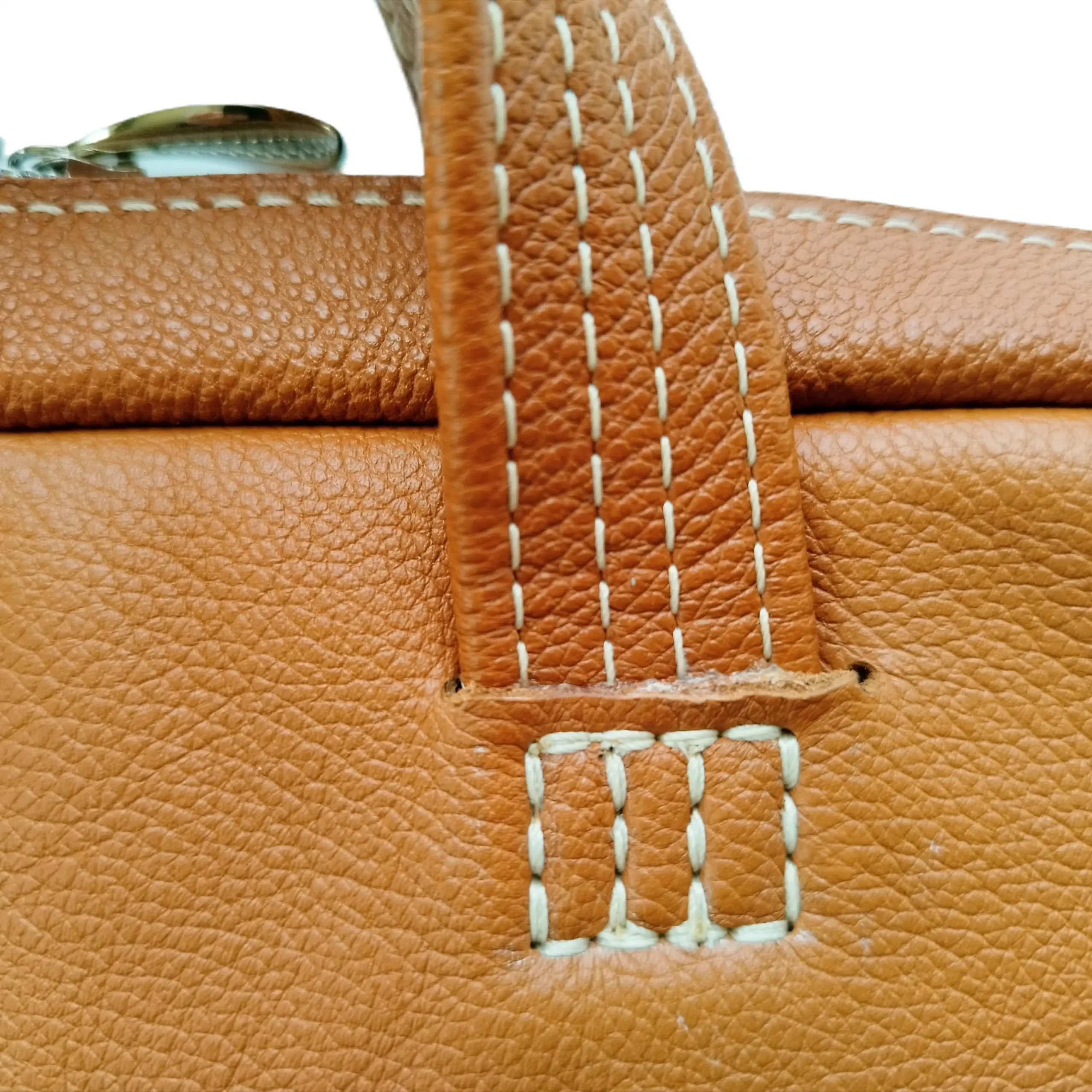 Détail de la fixation de poignée sur le sac ordinateur en cuir pleine fleur camel.